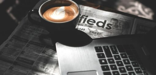 Taza de café junto a un portátil sobre una mesa de trabajo