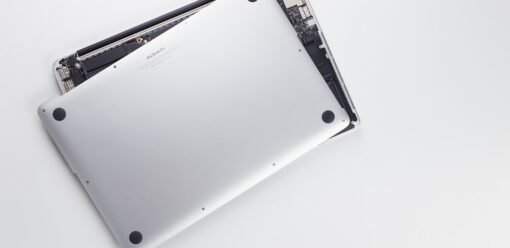 Técnico revisando la pantalla abierta de un MacBook en banco limpio