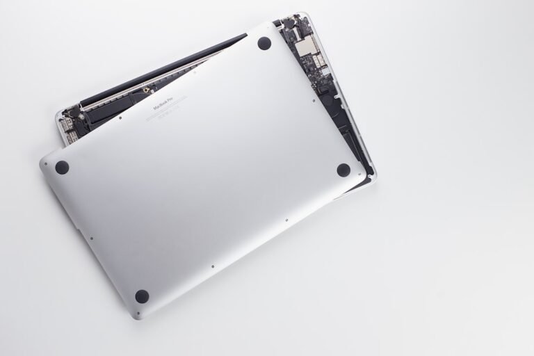 Técnico revisando la pantalla abierta de un MacBook en banco limpio