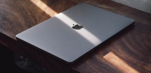 Portátil Apple sobre una mesa de madera en un entorno profesional