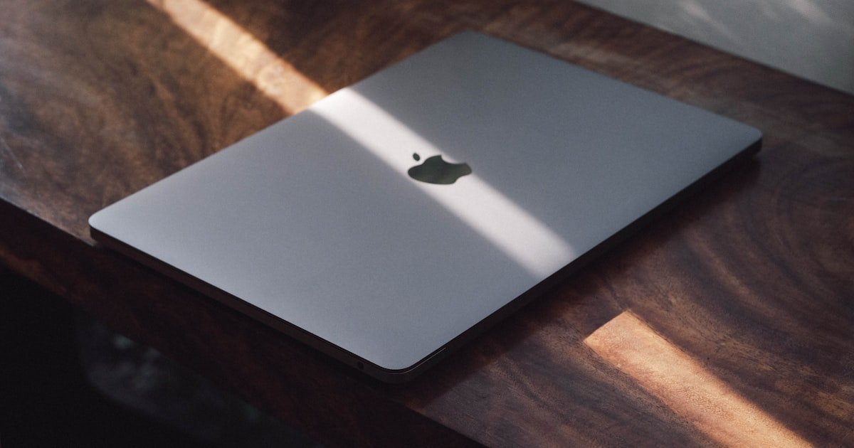 Portátil Apple sobre una mesa de madera en un entorno profesional
