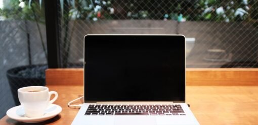 MacBook junto a una taza de café en una mesa de trabajo