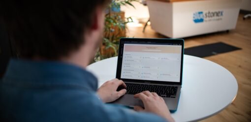 Usuario trabajando con un MacBook en una mesa blanca