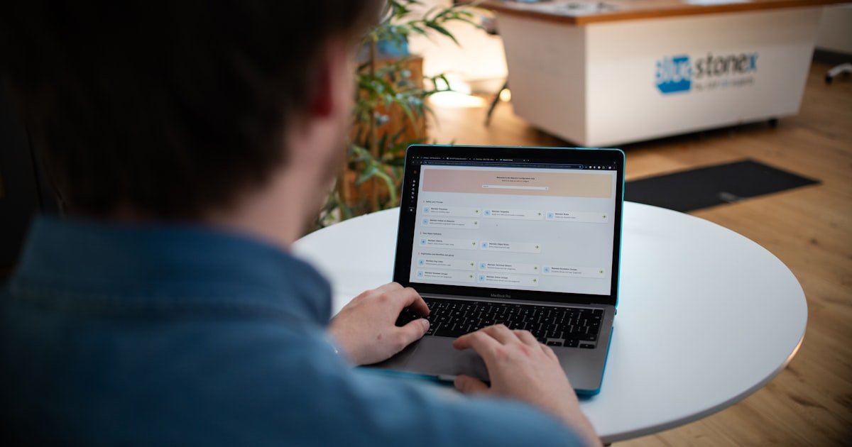 Usuario trabajando con un MacBook en una mesa blanca