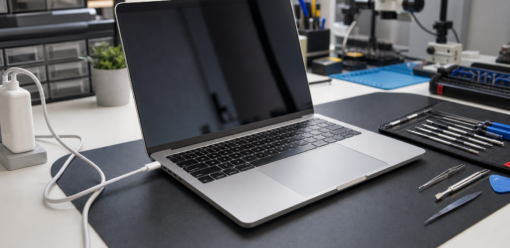 MacBook conectado a un cargador sobre una mesa de trabajo tecnico
